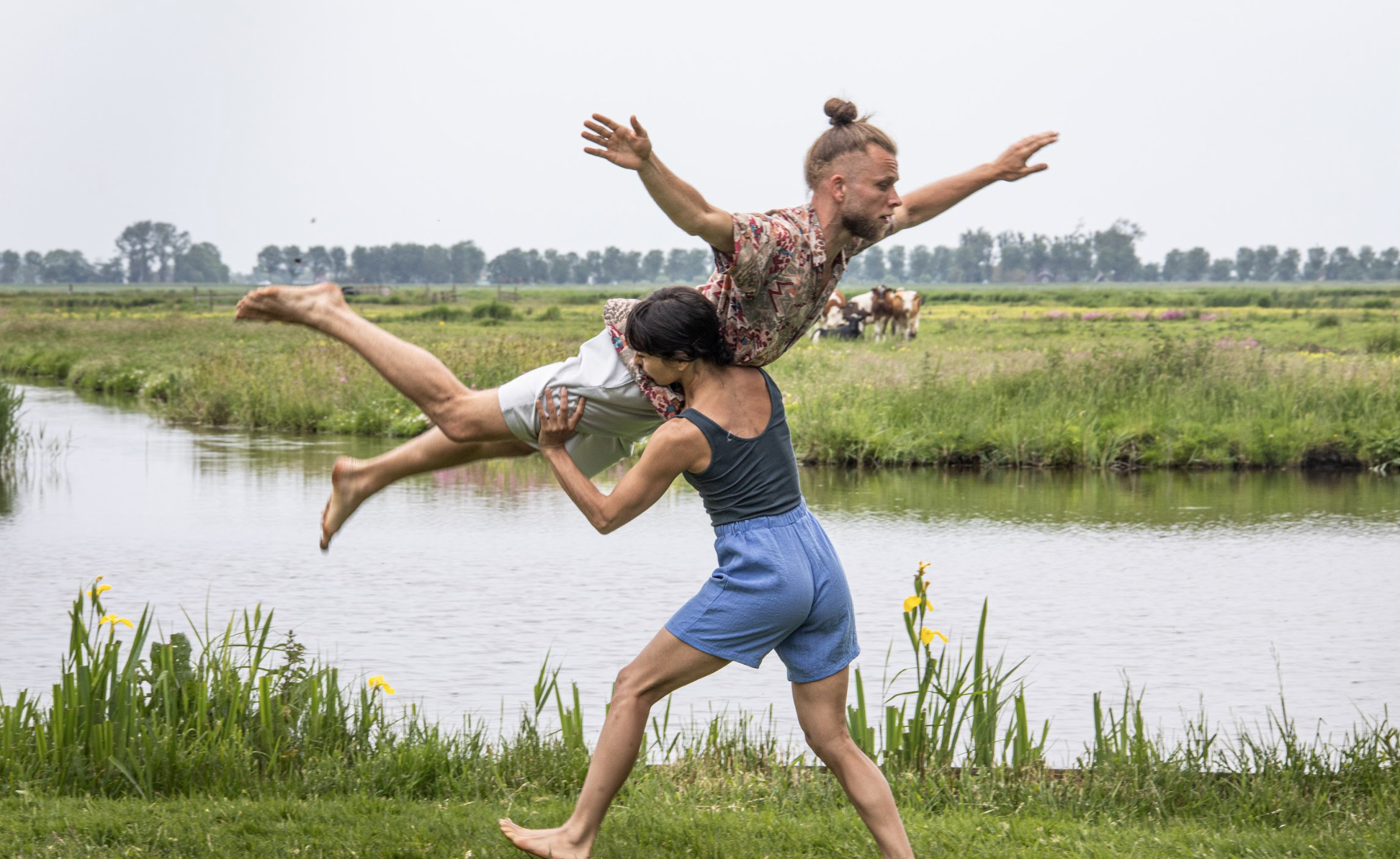 Dans, if you scream i whisper: een danseres lift een danser met op de achtergrond de polder