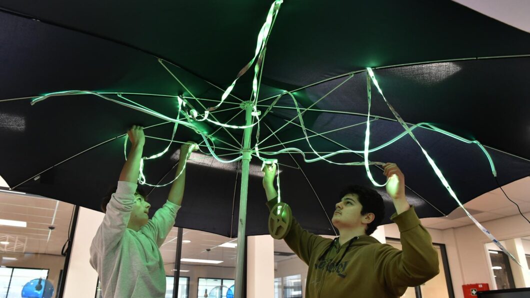 Mehrdad (rechts) en Max hangen de led-verlichting in de parasol